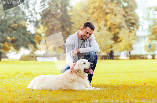 Image of happy man with labrador dog in autumn city park