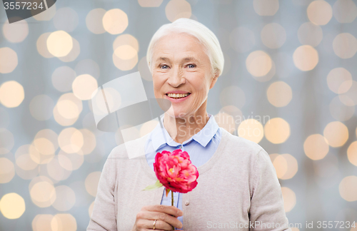 Image of happy smiling senior woman with flower at home