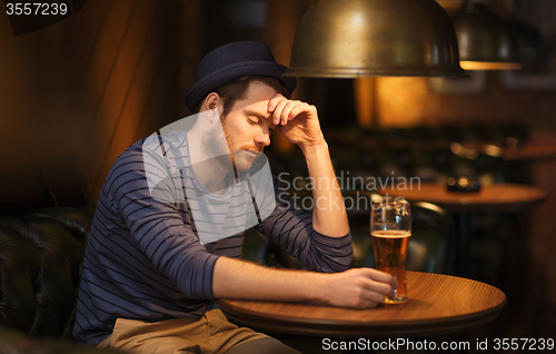 Image of unhappy lonely man drinking beer at bar or pub