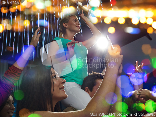 Image of friends with smartphone taking picture at concert