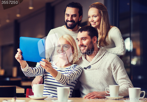 Image of happy friends with tablet pc taking selfie at cafe