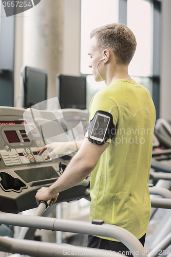 Image of man with smartphone exercising on treadmill in gym