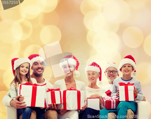 Image of happy family in santa helper hats with gift boxes