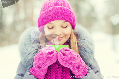 Image of smiling young woman with cup in winter forest