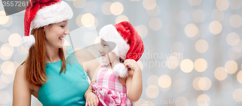 Image of happy mother and little girl in santa hats