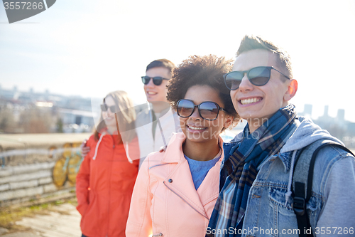 Image of happy teenage friends in shades hugging on street