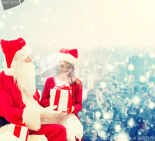 Image of smiling little girl with santa claus and gifts