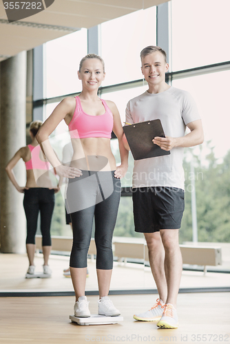 Image of smiling man and woman with scales in gym