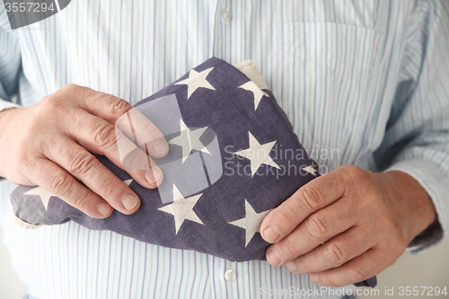 Image of Man holds folded American flag.	