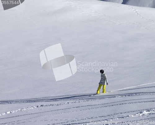 Image of Snowboarder downhill on off piste slope with newly-fallen snow