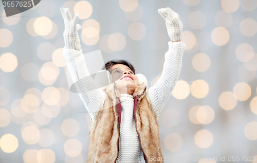 Image of happy little girl in earmuffs over holidays lights