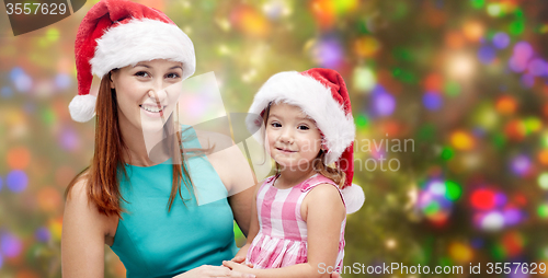Image of happy mother and little girl in santa hats