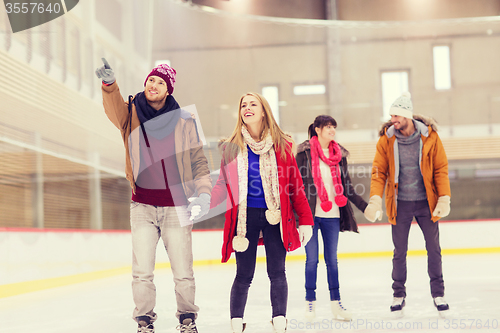 Image of happy friends pointing finger on skating rink