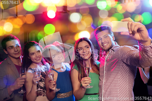 Image of friends with glasses and smartphone in club