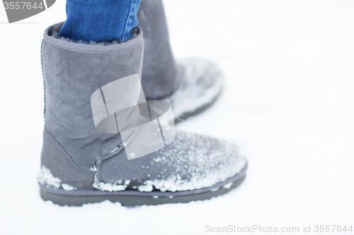 Image of close up of woman legs wearing warm boots on snow