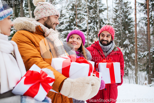 Image of happy friends with gift boxes in winter forest