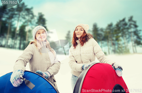 Image of happy girl friends with snow tubes outdoors