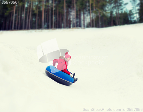 Image of happy teenage girl sliding down on snow tube