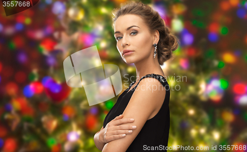 Image of beautiful woman wearing earrings over lights