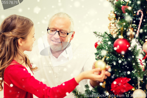 Image of smiling family decorating christmas tree at home