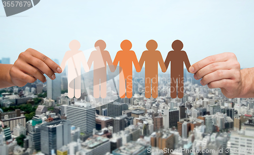 Image of hands with people pictogram over city background