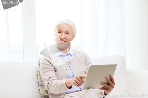 Image of happy senior woman with tablet pc at home