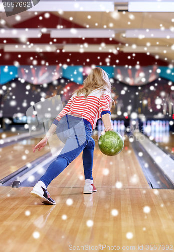 Image of happy young woman throwing ball in bowling club