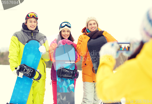 Image of happy friends with snowboards and smartphone