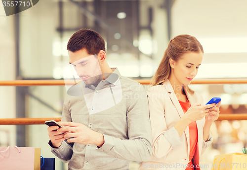 Image of couple with smartphones and shopping bags in mall