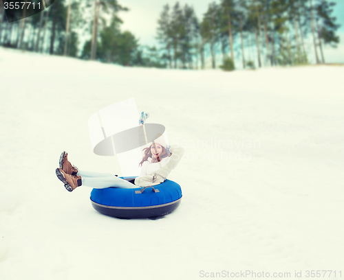 Image of happy teenage girl sliding down on snow tube