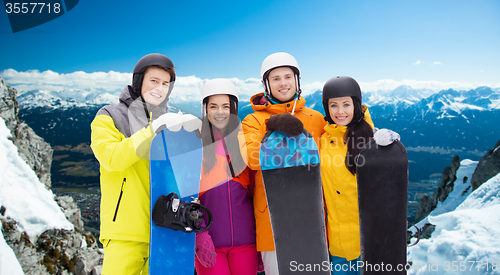 Image of happy friends in helmets with snowboards outdoors