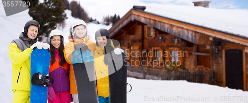 Image of happy friends in helmets with snowboards outdoors