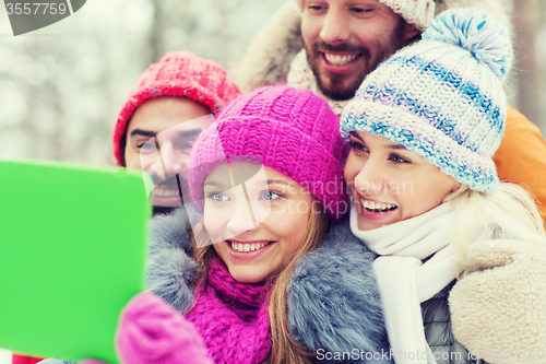 Image of smiling friends with tablet pc in winter forest