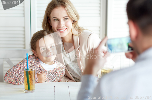 Image of happy family picturing by smartphone at restaurant