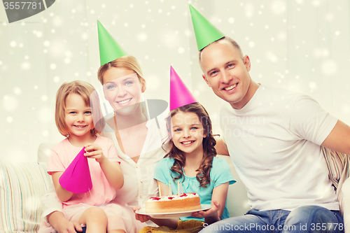 Image of happy family with two kids in party hats at home