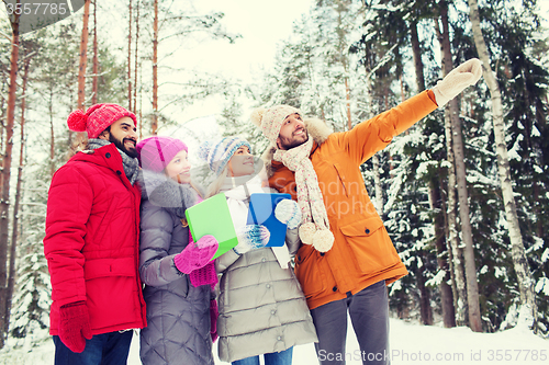 Image of smiling friends with tablet pc in winter forest