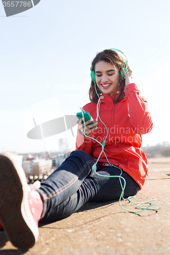 Image of happy young woman with smartphone and headphones