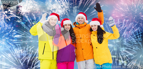 Image of happy friends in santa hats and ski suits outdoors