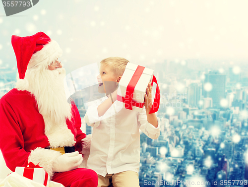 Image of smiling little boy with santa claus and gifts