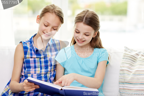 Image of two happy girls reading book at home