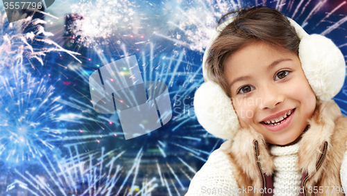 Image of happy little girl wearing earmuffs over firework