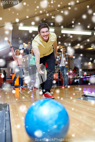 Image of happy young man throwing ball in bowling club