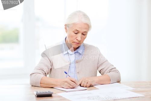 Image of senior woman with papers and calculator at home