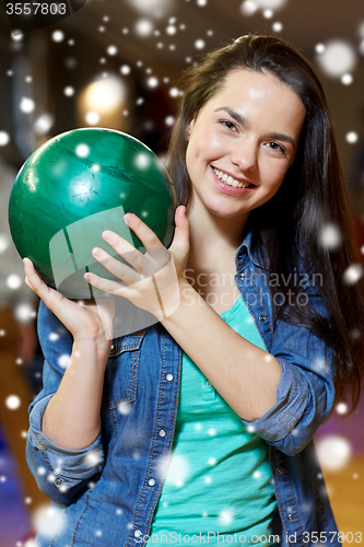 Image of happy young woman holding ball in bowling club