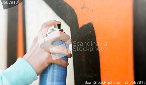 Image of close up of hand drawing graffiti with spray paint