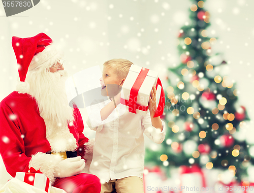 Image of smiling little boy with santa claus and gifts