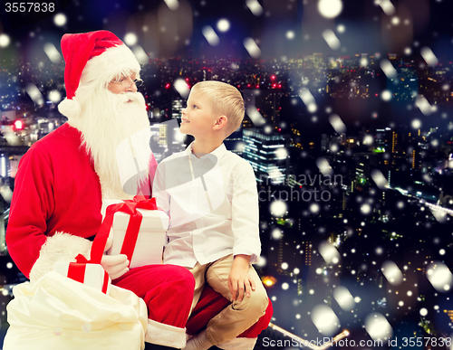 Image of smiling little boy with santa claus and gifts