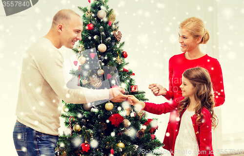 Image of smiling family decorating christmas tree at home