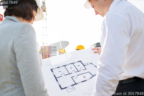 Image of close up of architects with blueprint at building