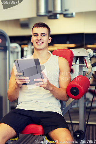 Image of smiling young man with tablet pc computer in gym